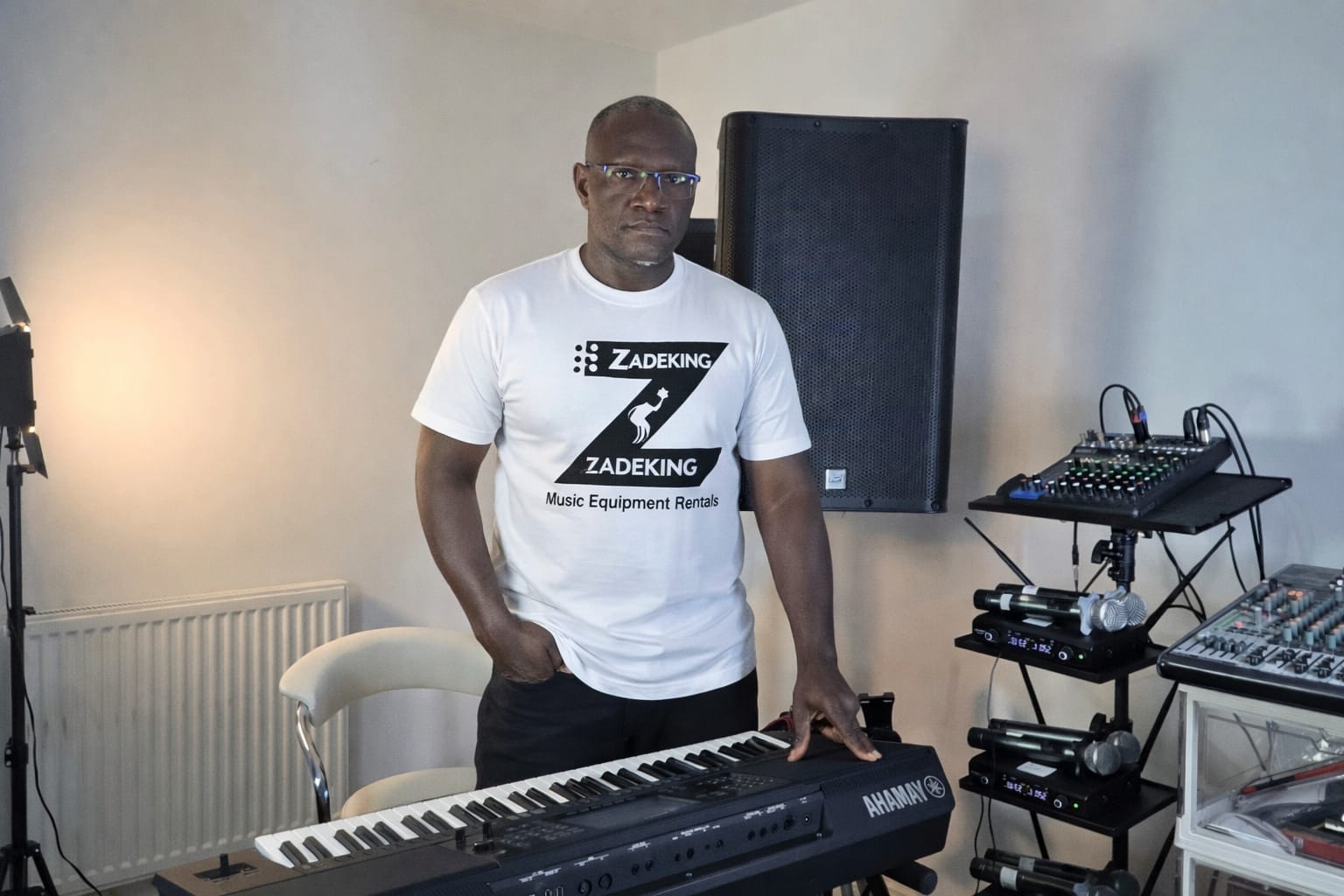 Zadeking owner wearing branded t-shirt in studio with speakers and keyboard